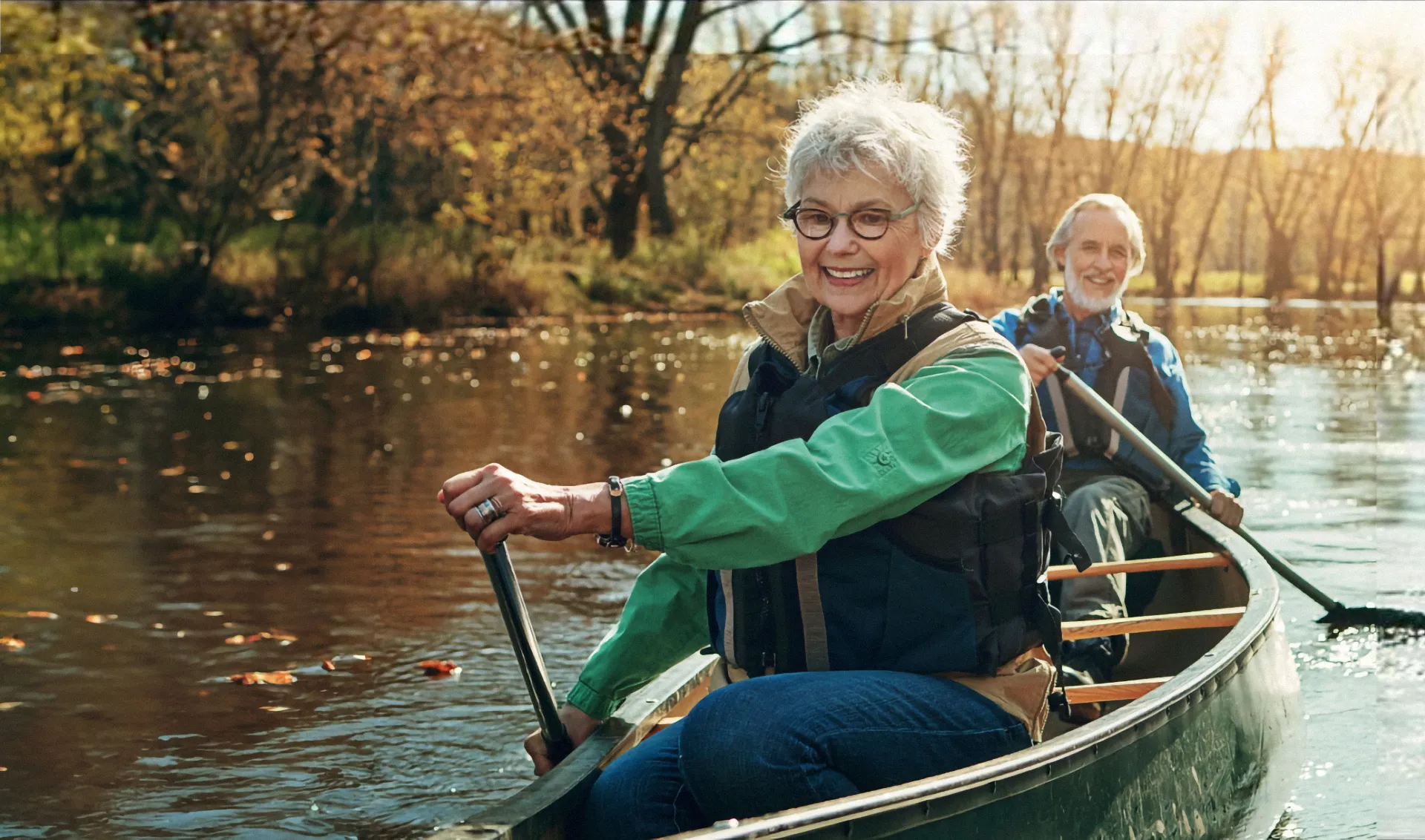 Senior couple paddling a canoe on a calm autumn river