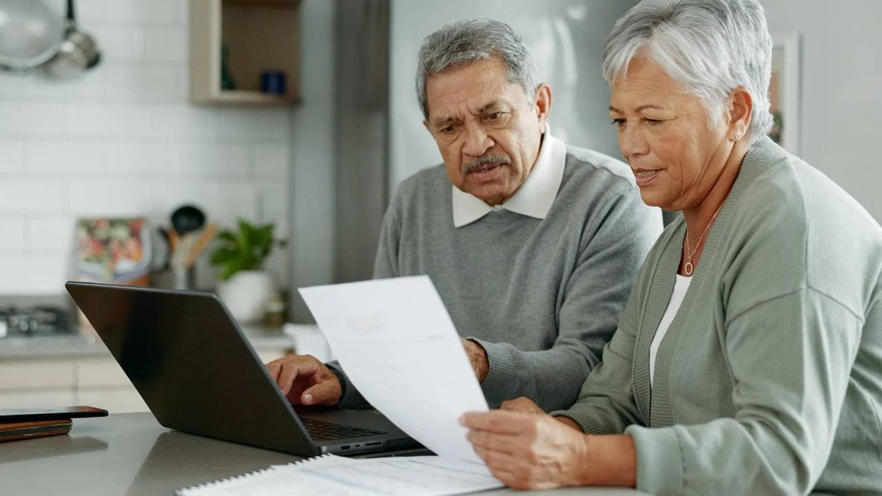 A retired couple reviewing documents together at a laptop