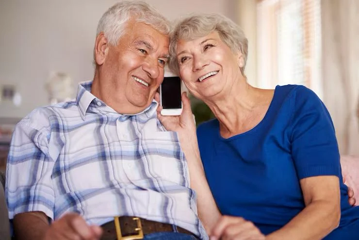 A retired couple at home, sharing a phone call.