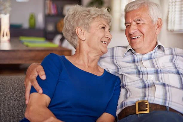 A retired couple relaxing together on the couch at home.