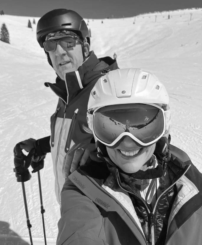 A couple in ski gear smiling on a sunny mountain slope